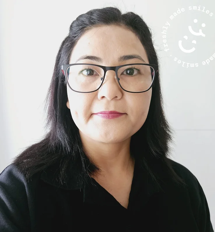 Porträt einer EatHappy Mitarbeiterin mit Brille und schwarzem Oberteil vor hellem Hintergrund