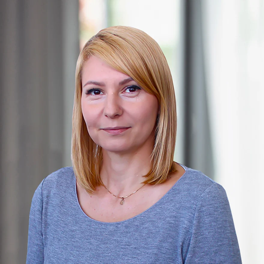 Porträt einer EatHappy Mitarbeiterin mit blondem Haar und grauem Oberteil vor hellem Hintergrund